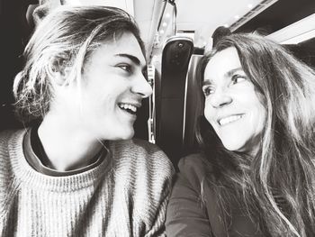 Close-up portrait of smiling mother and son sitting in train