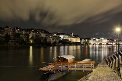 Boat moored by jetty in river against sky at night