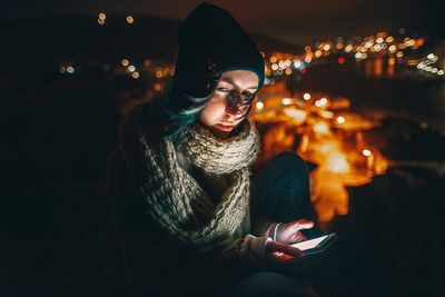 Portrait of young woman sitting in park during winter
