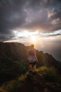 Rear view of man standing on mountain against sky