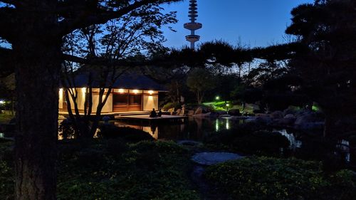 Gazebo by lake against sky at night