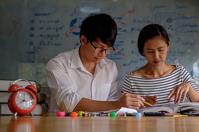 Friends studying with school supplies on table at home