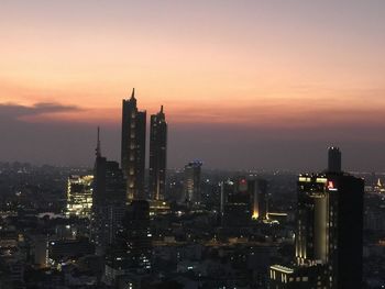 Illuminated buildings against sky during sunset