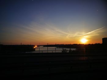 Silhouette bridge over sea against sky during sunset