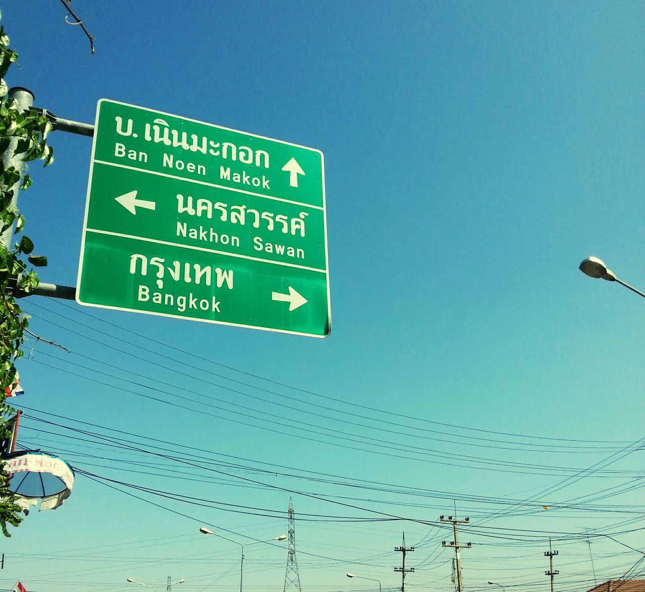 communication, text, blue, low angle view, western script, clear sky, guidance, information sign, sign, road sign, information, copy space, arrow symbol, capital letter, directional sign, pole, direction, street light, power line, day