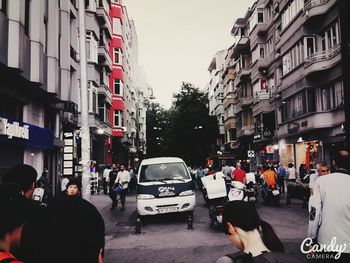 People walking on road in city against clear sky