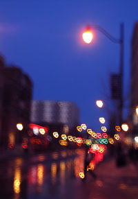 Illuminated street lights against buildings at night