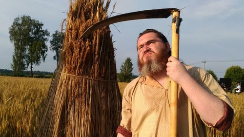 Portrait of man standing on field against sky