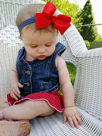 Cute baby girl sitting on chair at yard
