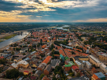 Aerial view of buildings and river against cloudy sky at sunset