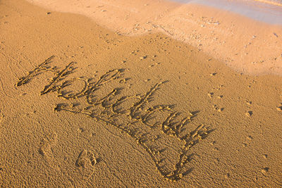 High angle view of holiday text on shore at beach