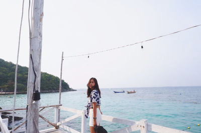 Portrait of young woman standing in sea against clear sky