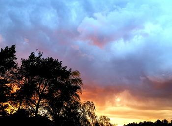 Low angle view of silhouette trees against dramatic sky