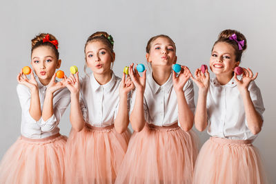 Portrait of girls holding colorful macaroons against white background