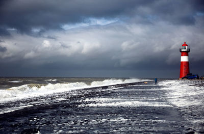 Lighthouse by sea against sky during winter