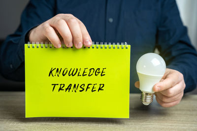 Midsection of man holding text on table