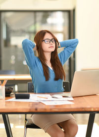 Young woman using mobile phone while sitting on table
