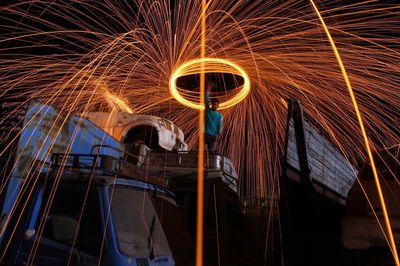 Low angle view of man on truck spinning wire wool at night