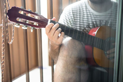 Midsection of man playing guitar