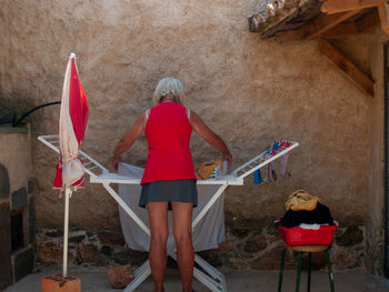 Rear view of women putting clothes on rack for drying