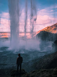 Rear view of man standing on shore against sky