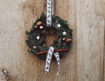 Close-up of christmas wreath hanging on wood