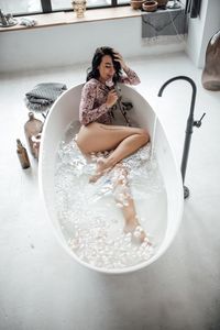 Beautiful woman sitting in bathtub