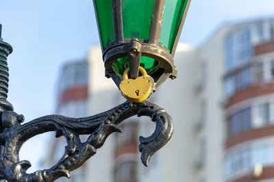Low angle view of lamp post with yellow pad lock against sky