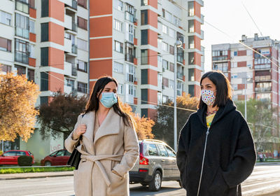 Two friends walking in city, wearing protective masks during corona virus epidemic, female, women.