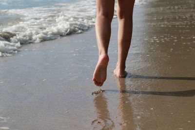 Low section of barefoot woman walking on beach