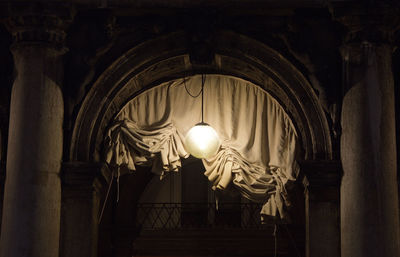 Low angle view of illuminated lamp hanging on ceiling in building