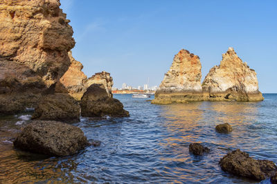 View of rock formation in sea against blue sky