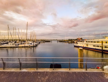 Sailboats moored at harbor against sky during sunset