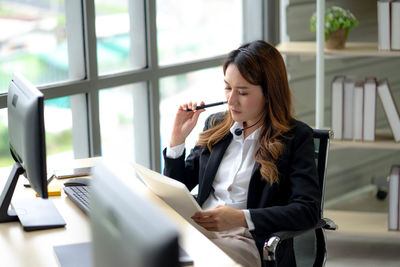 Young woman using mobile phone while sitting on table