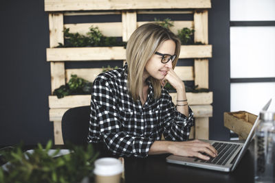 Young woman using mobile phone while sitting on table