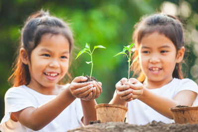 Happy girls holding saplings