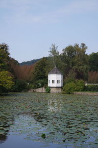 Built structure on lake by trees against sky