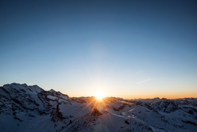 Scenic view of snowcapped mountains against clear sky during sunset