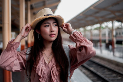 Portrait of beautiful young woman standing by railroad tracks