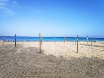 Wooden posts on beach against blue sky