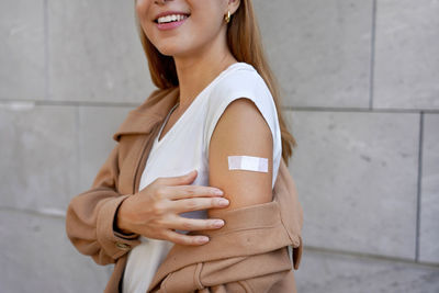 Vaccine campaign from covid-19. young beautiful healthy woman showing shoulder with plaster outdoor.