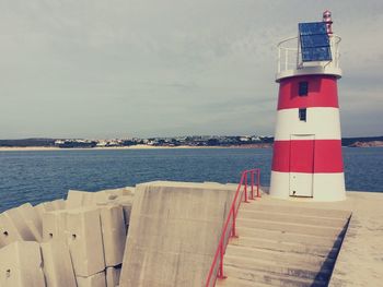 Lighthouse on sea against sky