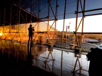 Silhouette man working at construction site against sky during sunset