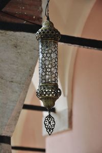 Low angle view of electric lamp hanging on wall in building