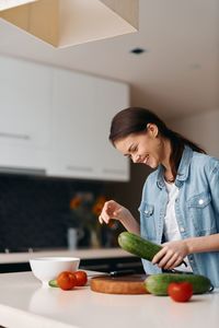 Portrait of young woman holding food in kitchen