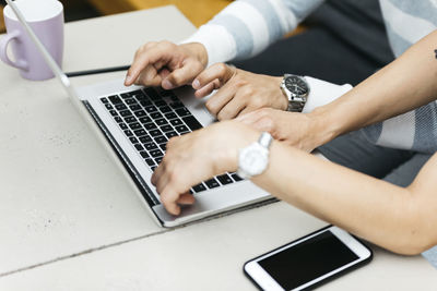 Close-up of man using laptop on table