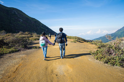 Rear view of people walking on mountain against sky