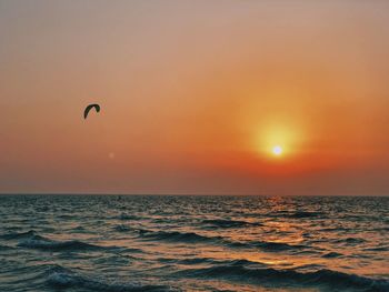 Scenic view of sea against sky during sunset with a silhouette of a wind surfer 