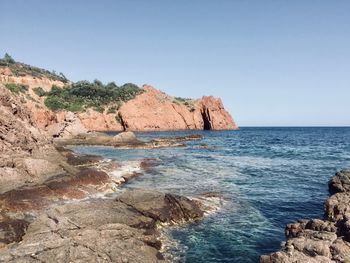 Scenic view of rocks in sea against clear sky