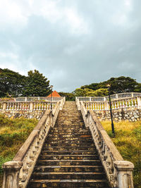 Footpath amidst trees against sky